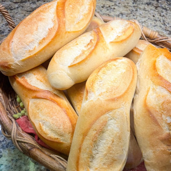 A rustic wicker basket overflows with freshly baked, golden-crusted Neapolitan Gourmet deli bread rolls.