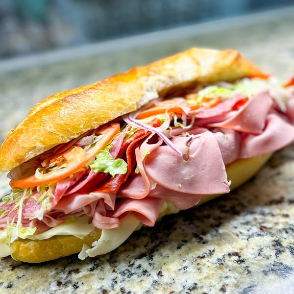 A large, fresh Neapolitan Gourmet deli sandwich with various meats, cheese, lettuce, and tomatoes.